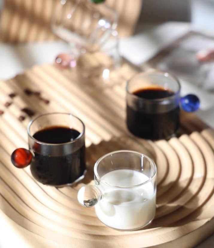 Transparent Glass Cup with a distinctive round ball handle, crafted from high borosilicate heat-resistant glass, showcasing a sleek design with a 5cm height and 5.5cm top diameter, perfect for hot beverages.