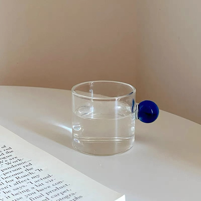Transparent Glass Cup with a distinctive round ball handle, crafted from high borosilicate heat-resistant glass, showcasing a sleek design with a 5cm height and 5.5cm top diameter, perfect for hot beverages.