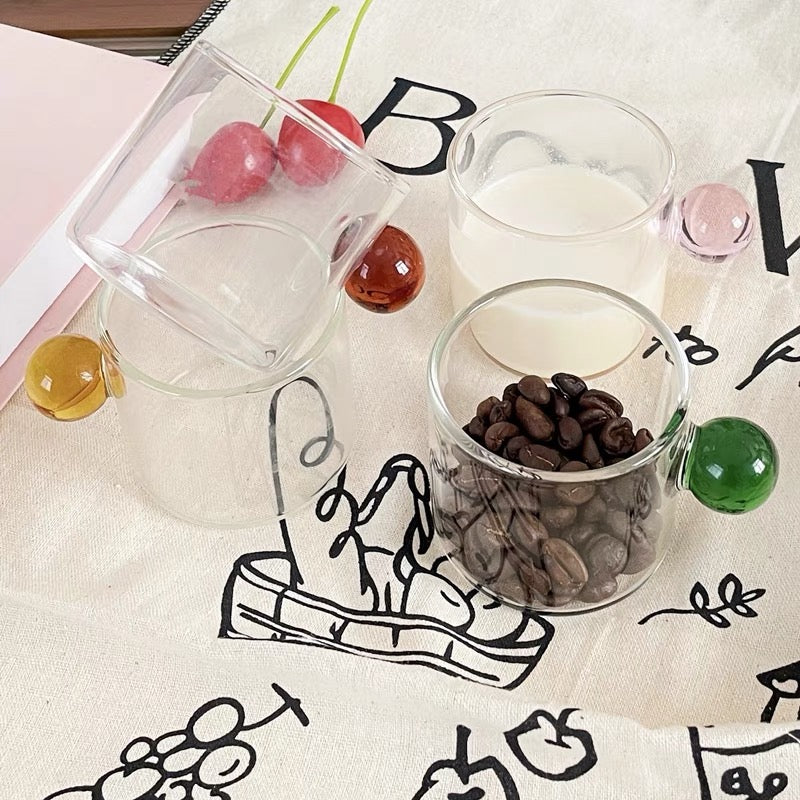 Transparent Glass Cup with a distinctive round ball handle, crafted from high borosilicate heat-resistant glass, showcasing a sleek design with a 5cm height and 5.5cm top diameter, perfect for hot beverages.