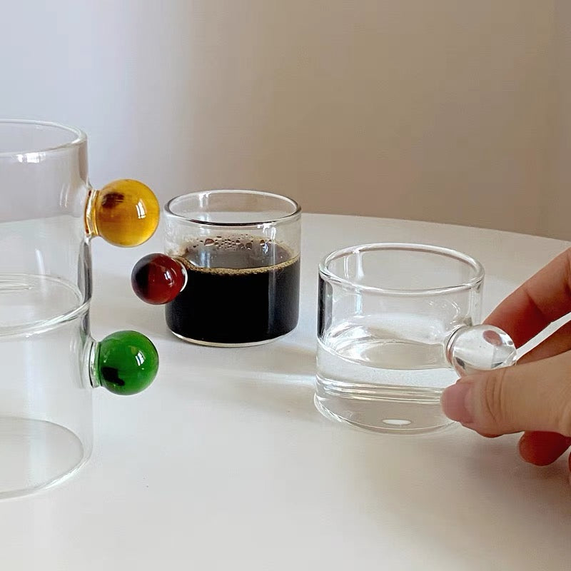 Transparent Glass Cup with a distinctive round ball handle, crafted from high borosilicate heat-resistant glass, showcasing a sleek design with a 5cm height and 5.5cm top diameter, perfect for hot beverages.