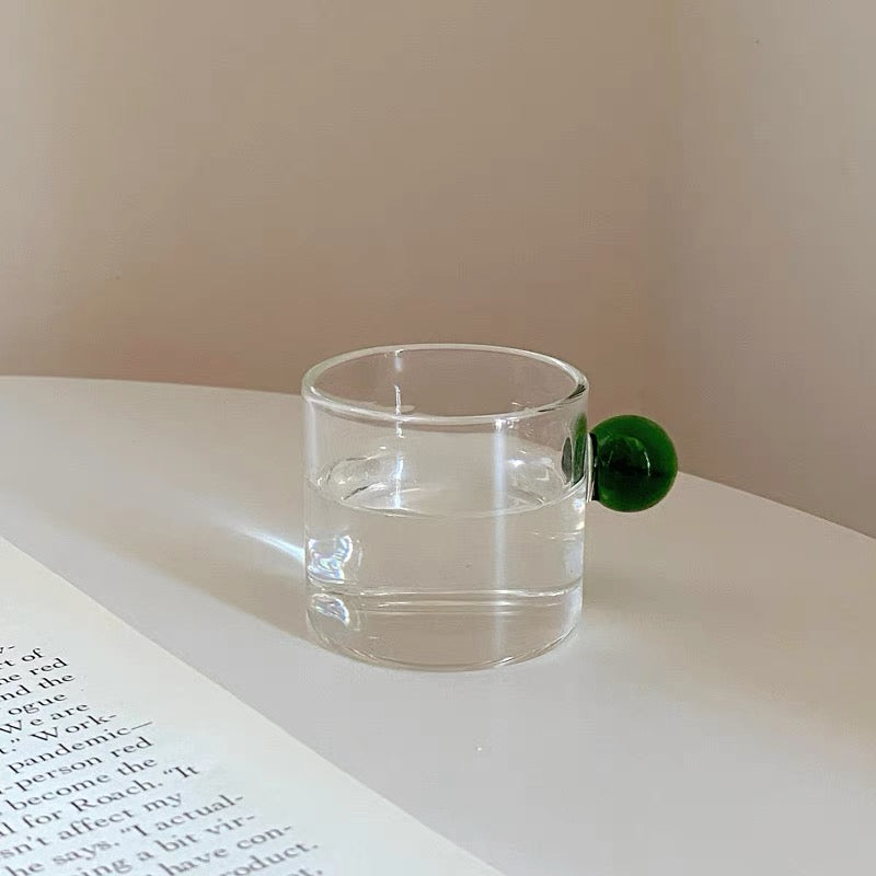 Transparent Glass Cup with a distinctive round ball handle, crafted from high borosilicate heat-resistant glass, showcasing a sleek design with a 5cm height and 5.5cm top diameter, perfect for hot beverages.