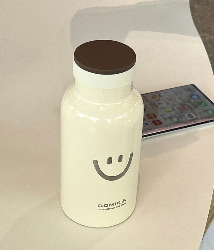 Yellow Smiley Face Thermal Bottle with a stainless steel inner lining, designed to keep beverages hot or cold. Iconic smiley face emblem prominently displayed on the front.